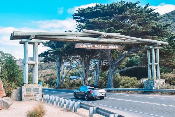 Car driving under Great Ocean Road entrance sign