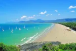 Scenic beach view with sailboats and lush greenery